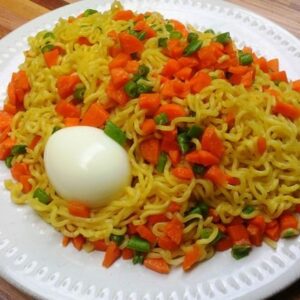 indomie and egg served with vegetables and 2 eggs